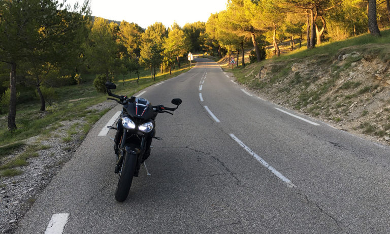 Moto roadster dans un virage sur route ouverte, trajectoire de sécurité