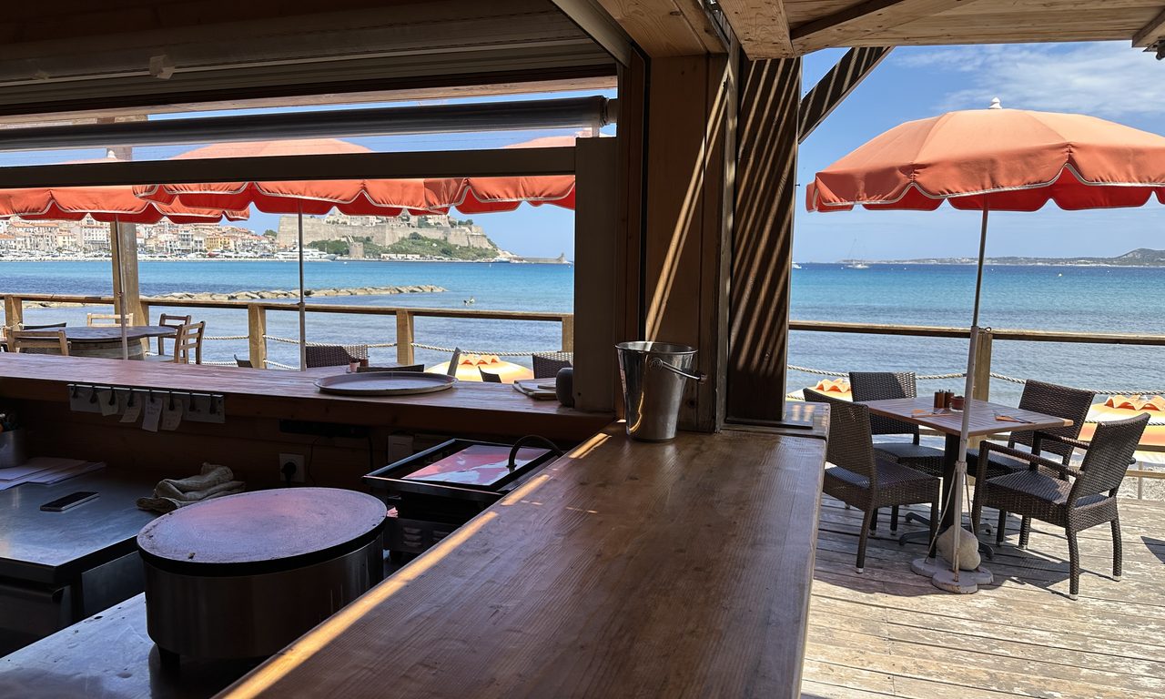 Intérieur de paillote en bois ouvert sur la mer et la citadelle de Calvi