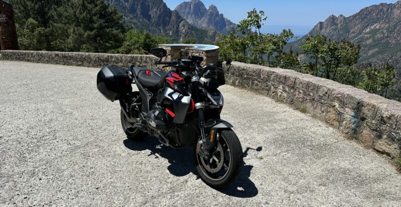 Moto garée à un belvédère face aux aiguilles rocheuses des calanques de Piana en Corse