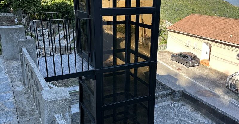 Ascenseur urbain vitré reliant deux niveaux d'un village corse à flanc de colline