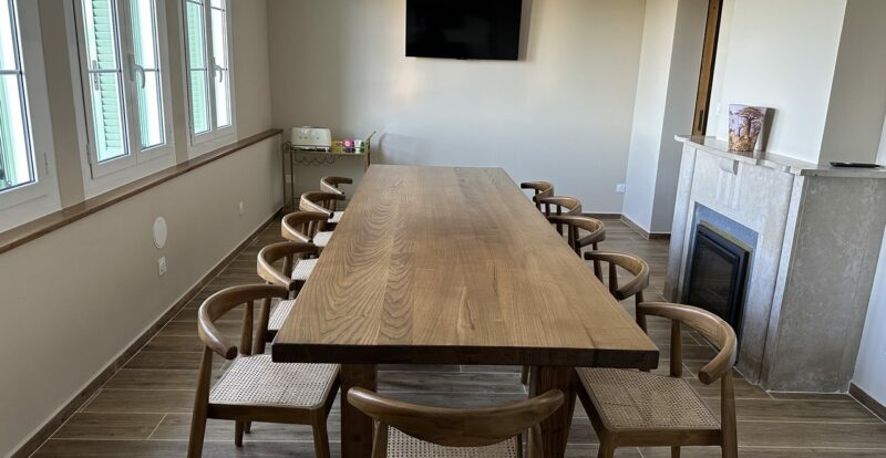 Salle à manger avec grande table en bois massif, chaises cannées et cheminée