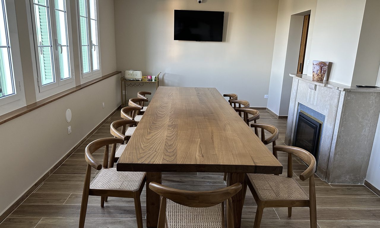 Salle à manger avec grande table en bois massif, chaises cannées et cheminée