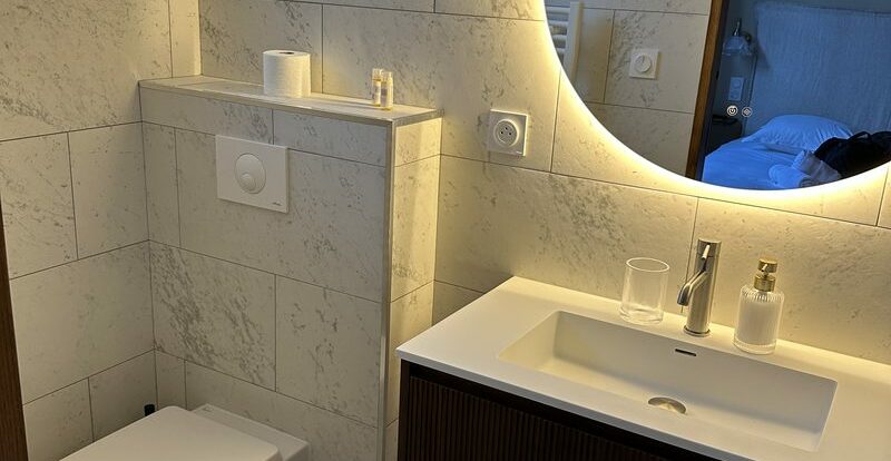 Salle de bain moderne avec vasque, miroir rond rétroéclairé et WC suspendu