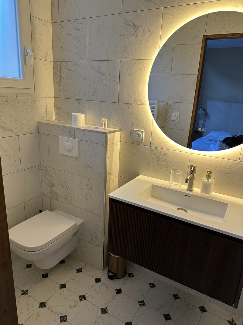 Salle de bain moderne avec vasque, miroir rond rétroéclairé et WC suspendu