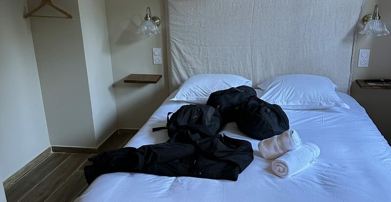 Chambre avec lit double, sacoches moto noires et serviettes roulées