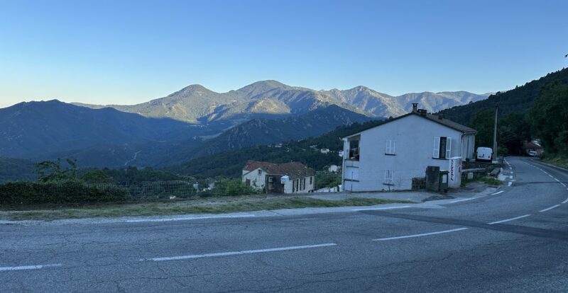 Village corse en montagne au lever du jour avec route et sommets boisés