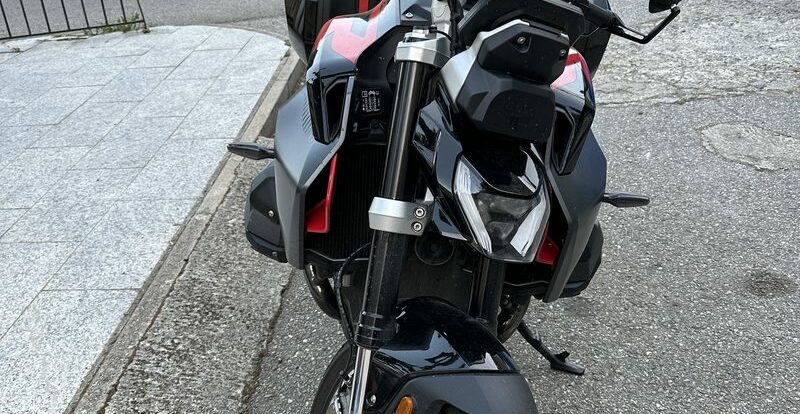 Roadster BMW gris et rouge garé dans une ruelle de village corse en pierre