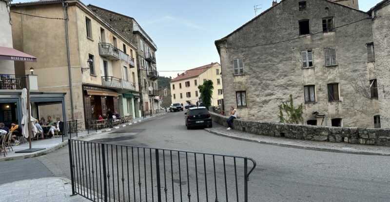 Place de village corse avec restaurant en terrasse et maisons anciennes