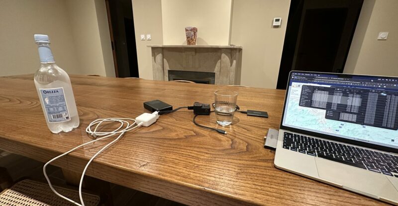 Table en bois avec eau Orezza, chargeurs et MacBook affichant une carte