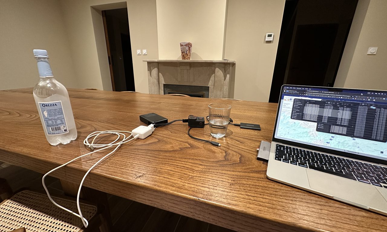 Table en bois avec eau Orezza, chargeurs et MacBook affichant une carte