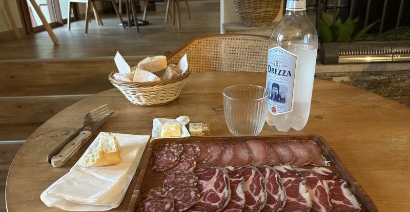 Planche de charcuterie corse et bouteille d'eau Orezza sur table en bois