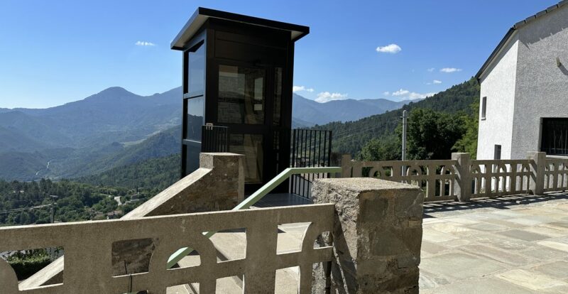 Terrasse panoramique d'un village corse avec ascenseur vitré face aux montagnes