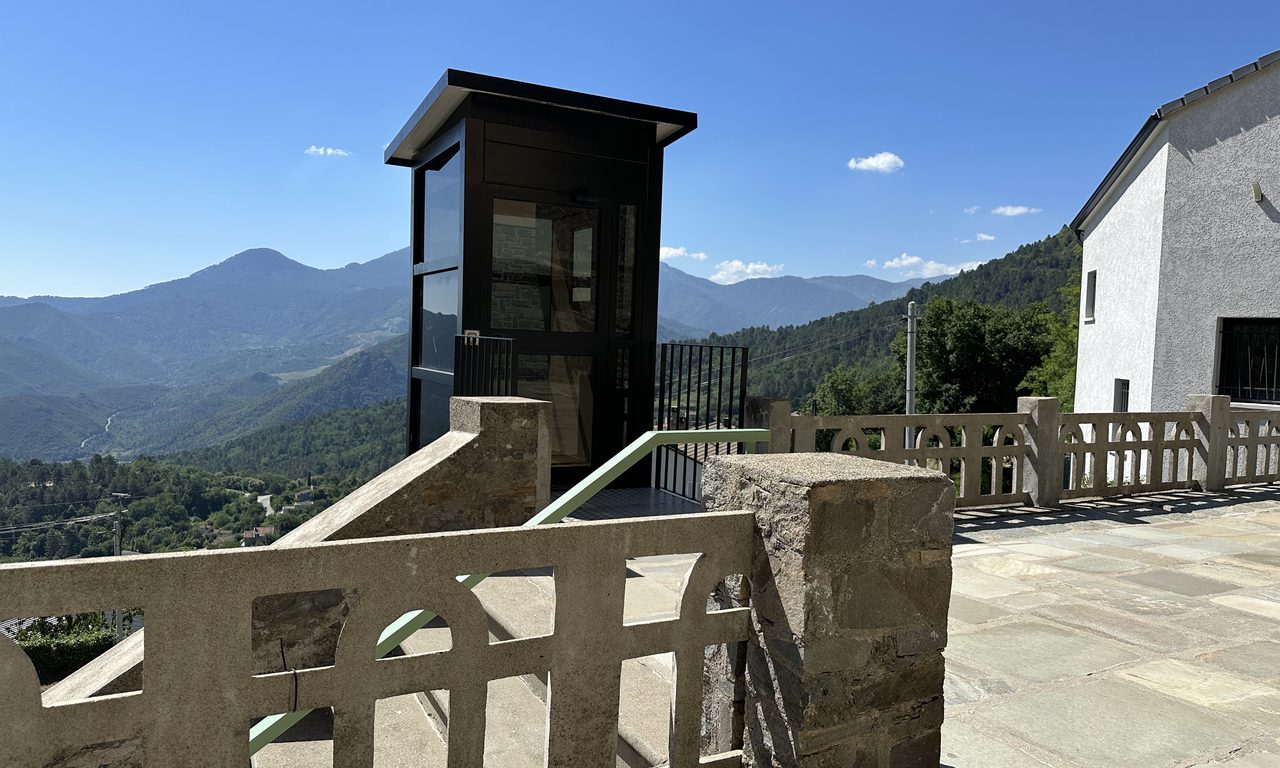Terrasse panoramique d'un village corse avec ascenseur vitré face aux montagnes