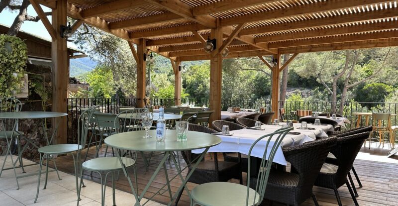 Terrasse de restaurant ombragée sous pergola en bois avec tables dressées