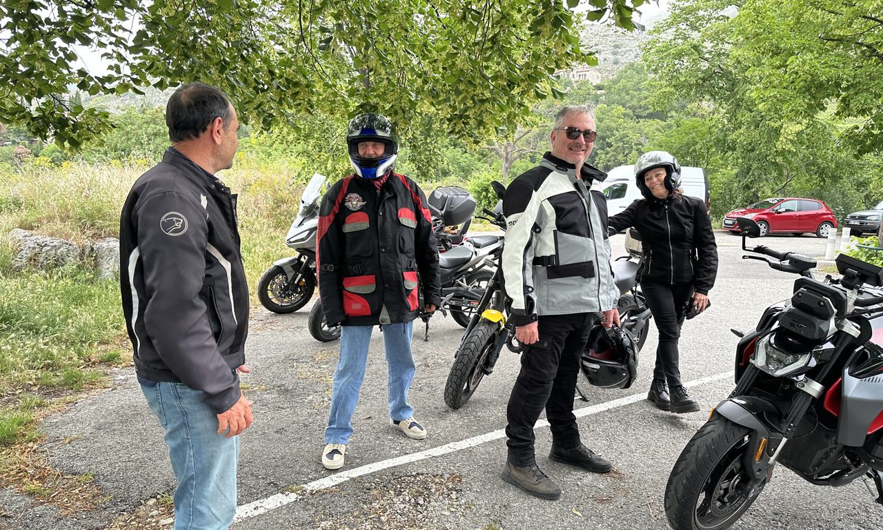 Motards discutent sur un parking ombragé