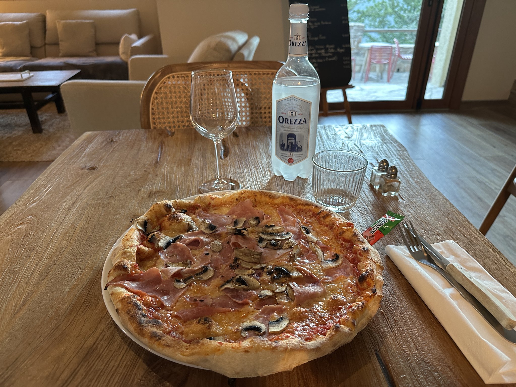 Pizza et Orezza sur une grande table en bois Chez Coco.